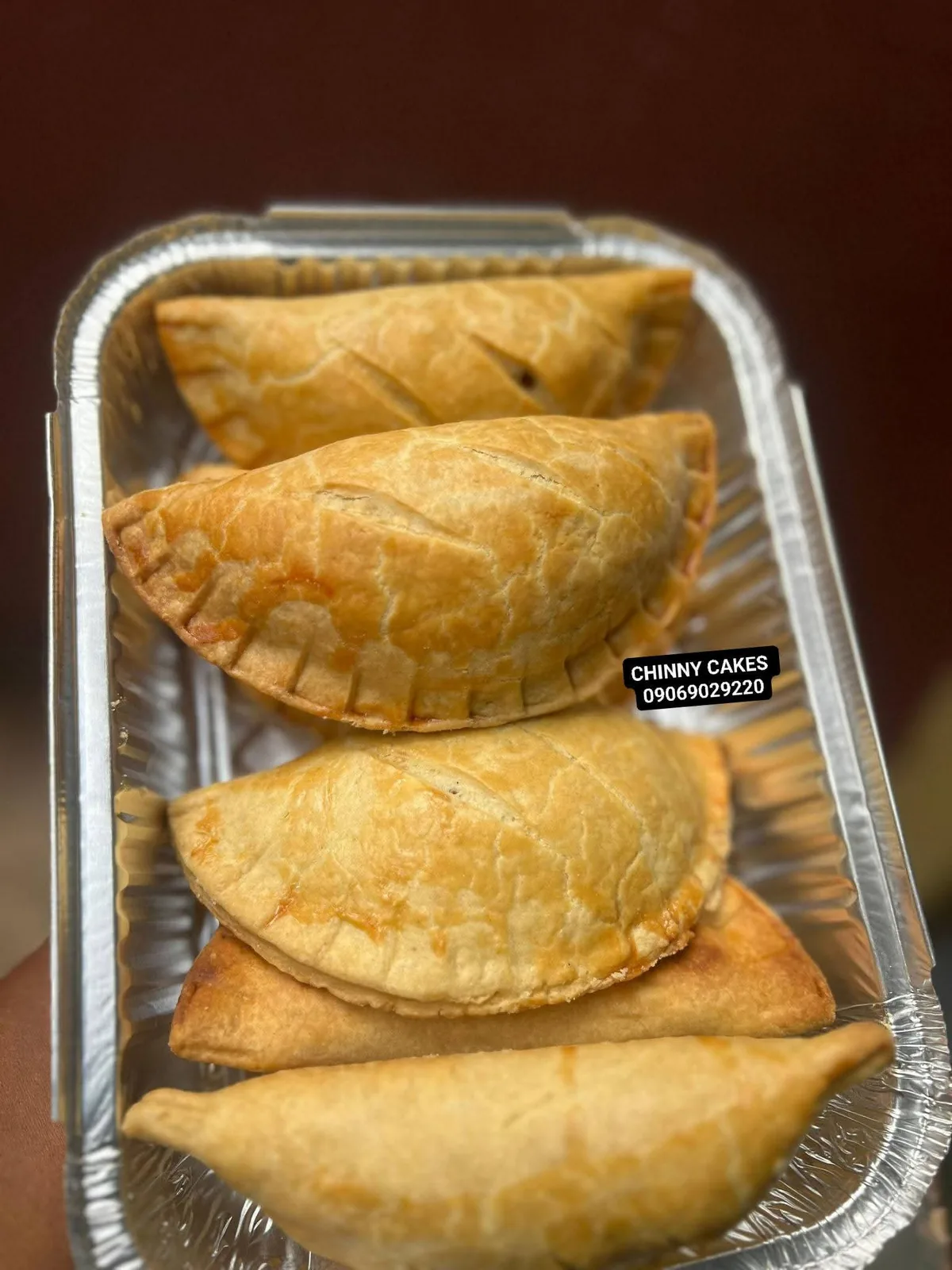 Golden pastries in a foil tray by Chinny Cakes & More