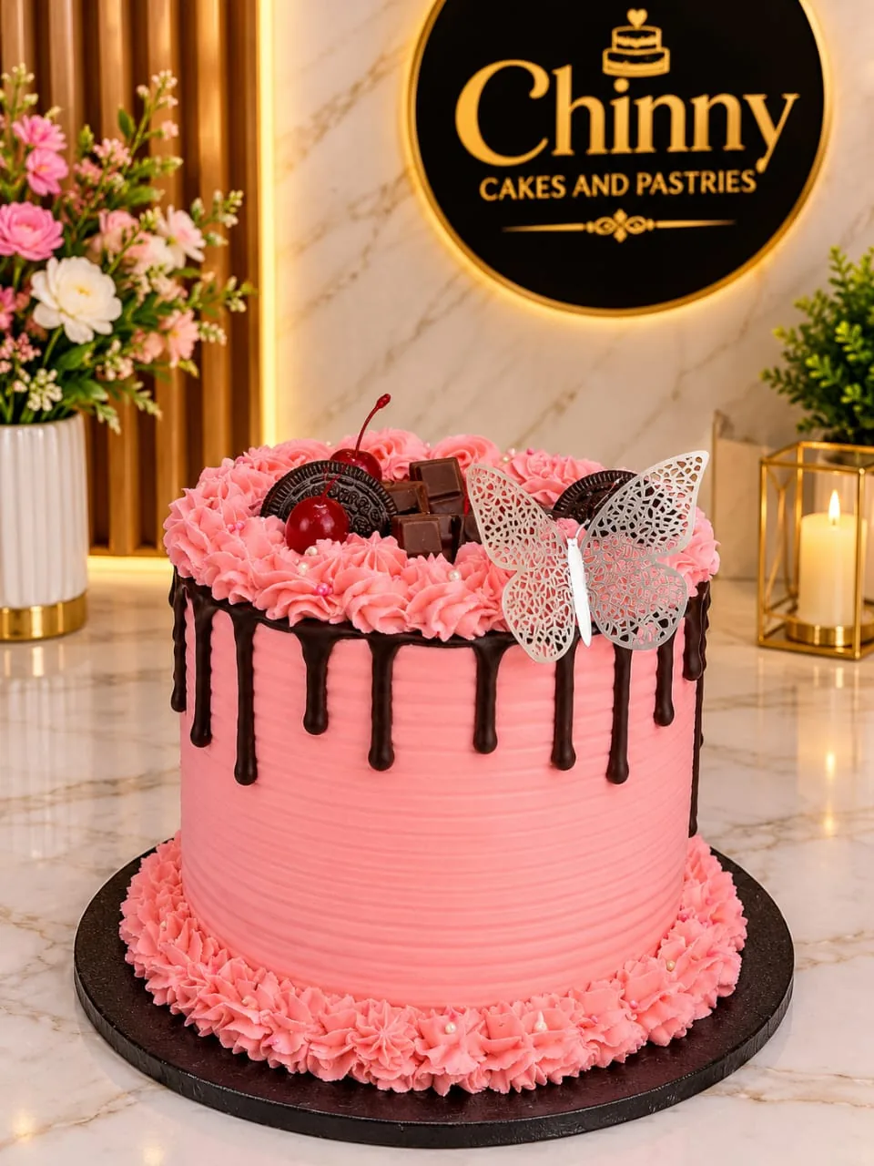 Pink birthday cake with chocolate drip, cookies, cherry and butterfly detail