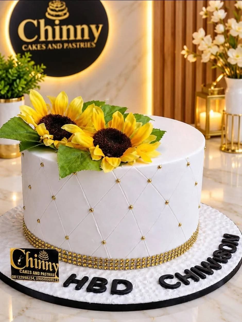 White celebration cake with sunflowers, quilted detailing and gold accents