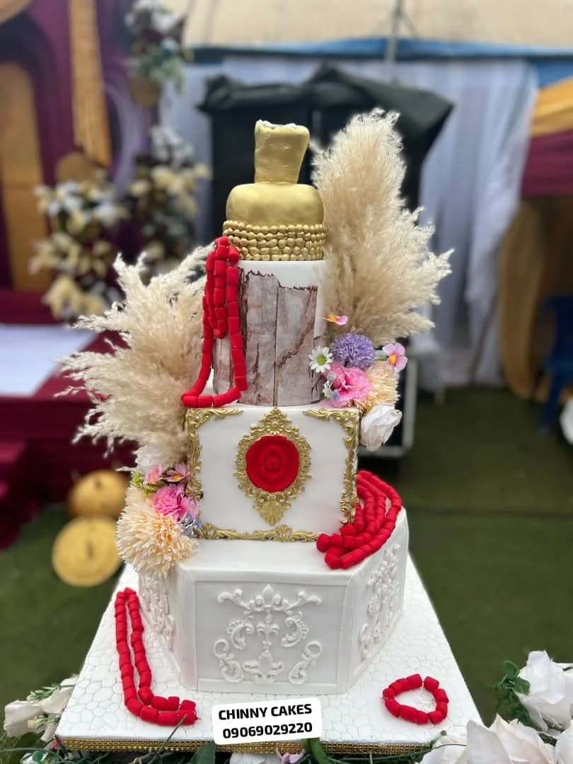 Tiered traditional celebration cake with white, gold and red decorative details